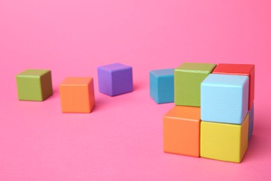 Photo of Many wooden colorful cubes on pink background