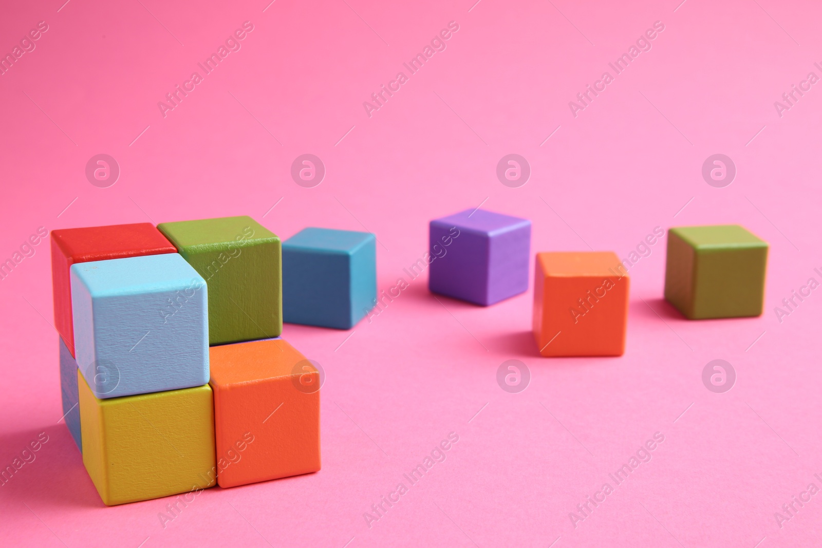 Photo of Many wooden colorful cubes on pink background