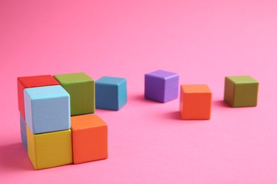 Photo of Many wooden colorful cubes on pink background