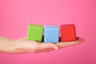 Photo of Woman with colorful cubes on pink background, closeup