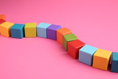 Photo of Many wooden colorful cubes on pink background