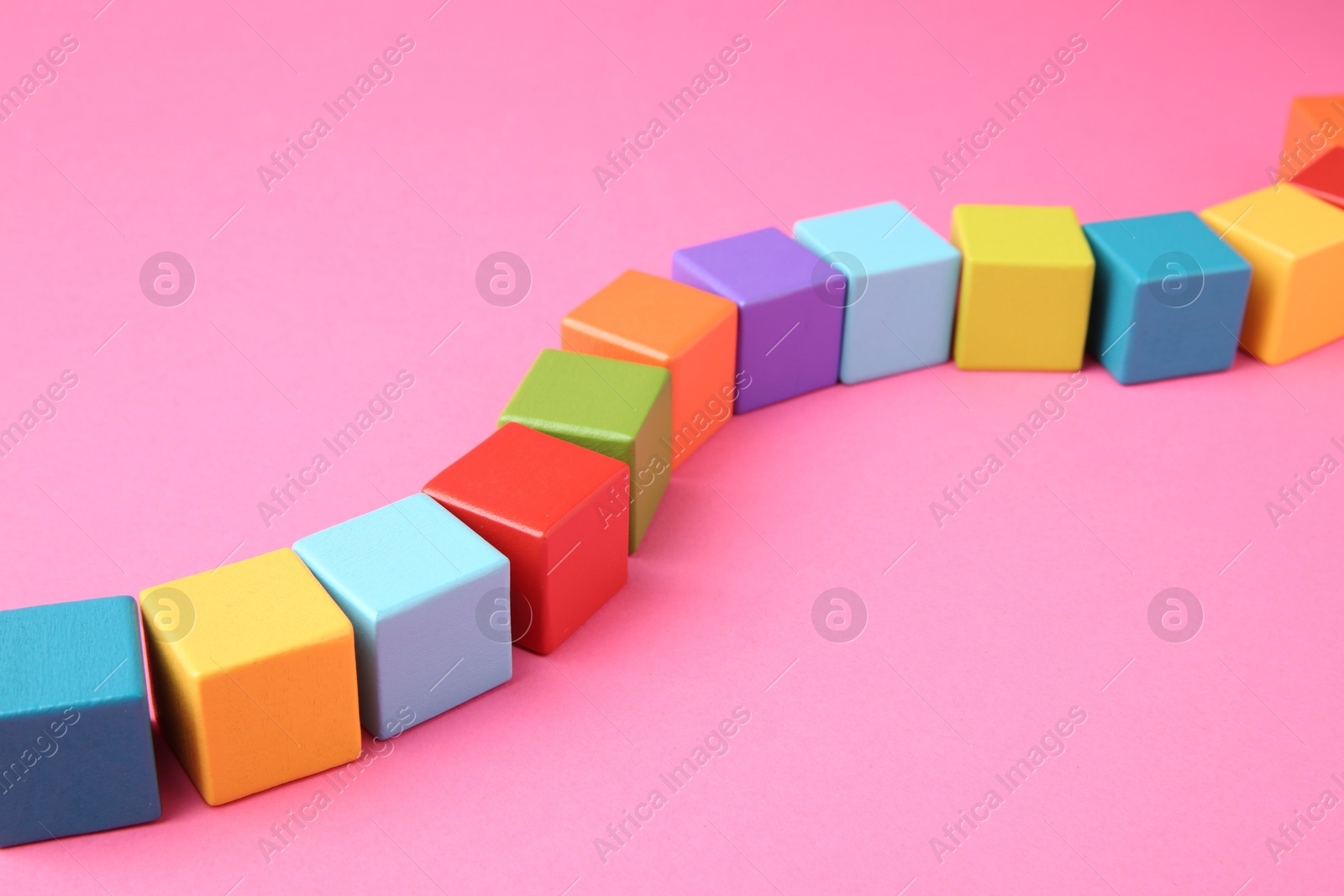 Photo of Many wooden colorful cubes on pink background