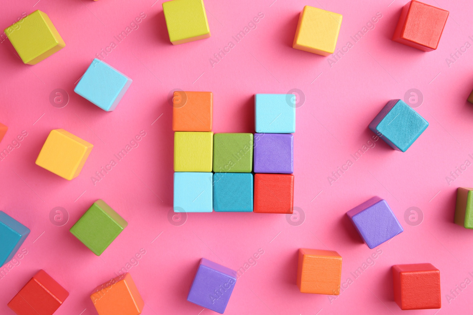 Photo of Many wooden colorful cubes on pink background, top view