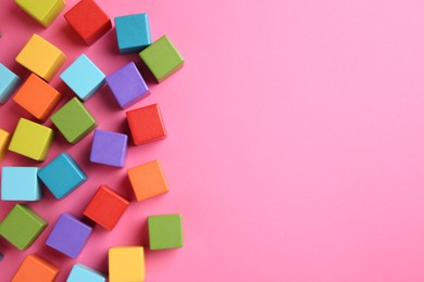 Photo of Many wooden colorful cubes on pink background, top view. Space for text