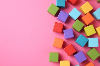 Photo of Many wooden colorful cubes on pink background, top view. Space for text