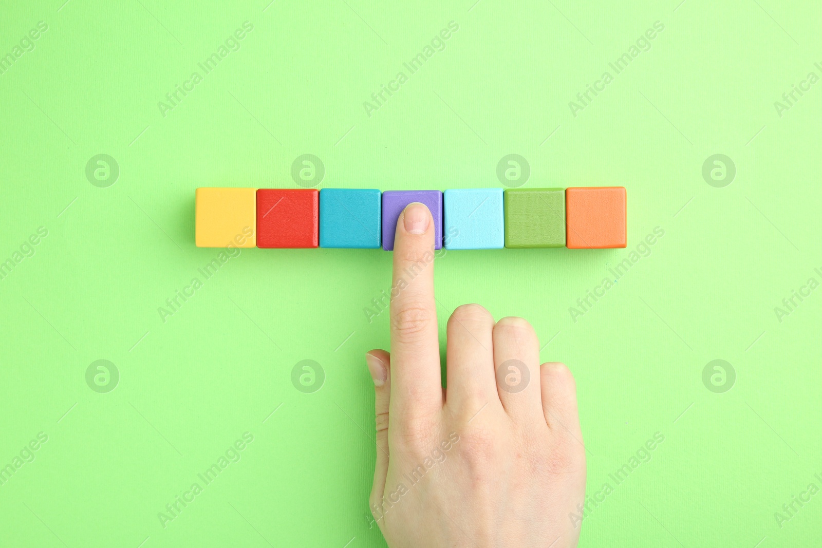 Photo of Woman with colorful cubes on green background, top view