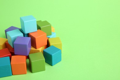 Photo of Many wooden colorful cubes on green background, space for text