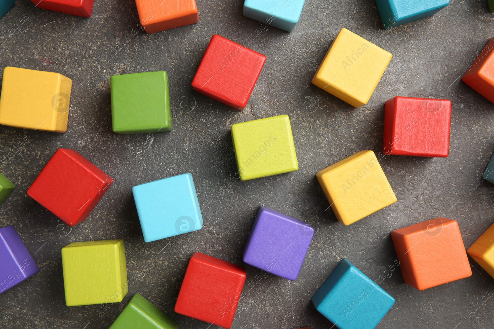 Photo of Many wooden colorful cubes on gray textured background, top view