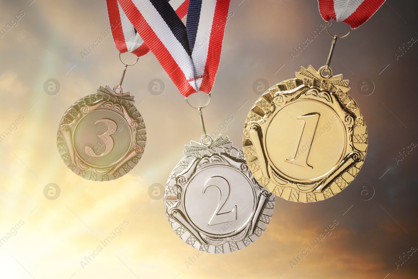 Image of Gold, silver and bronze medals against sky at sunset