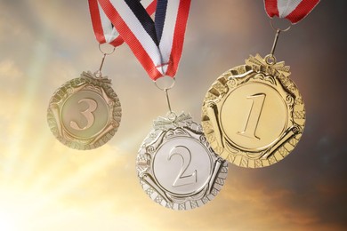 Image of Gold, silver and bronze medals against sky at sunset