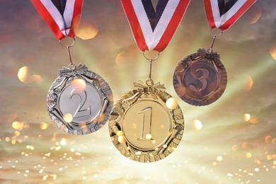 Image of Gold, silver and bronze medals against sky at sunset