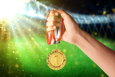 Woman with gold medal at sports field, closeup