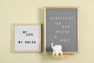 Photo of Letter boards with phrases Everything You Can Imagine Is Real, My Life My Rules and decor element on beige wall