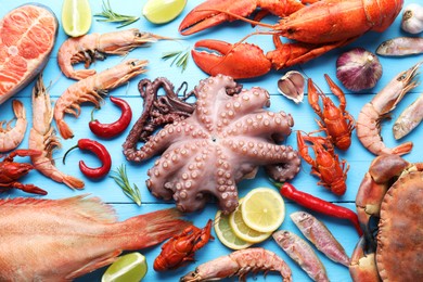 Different sea food on light blue wooden table, flat lay