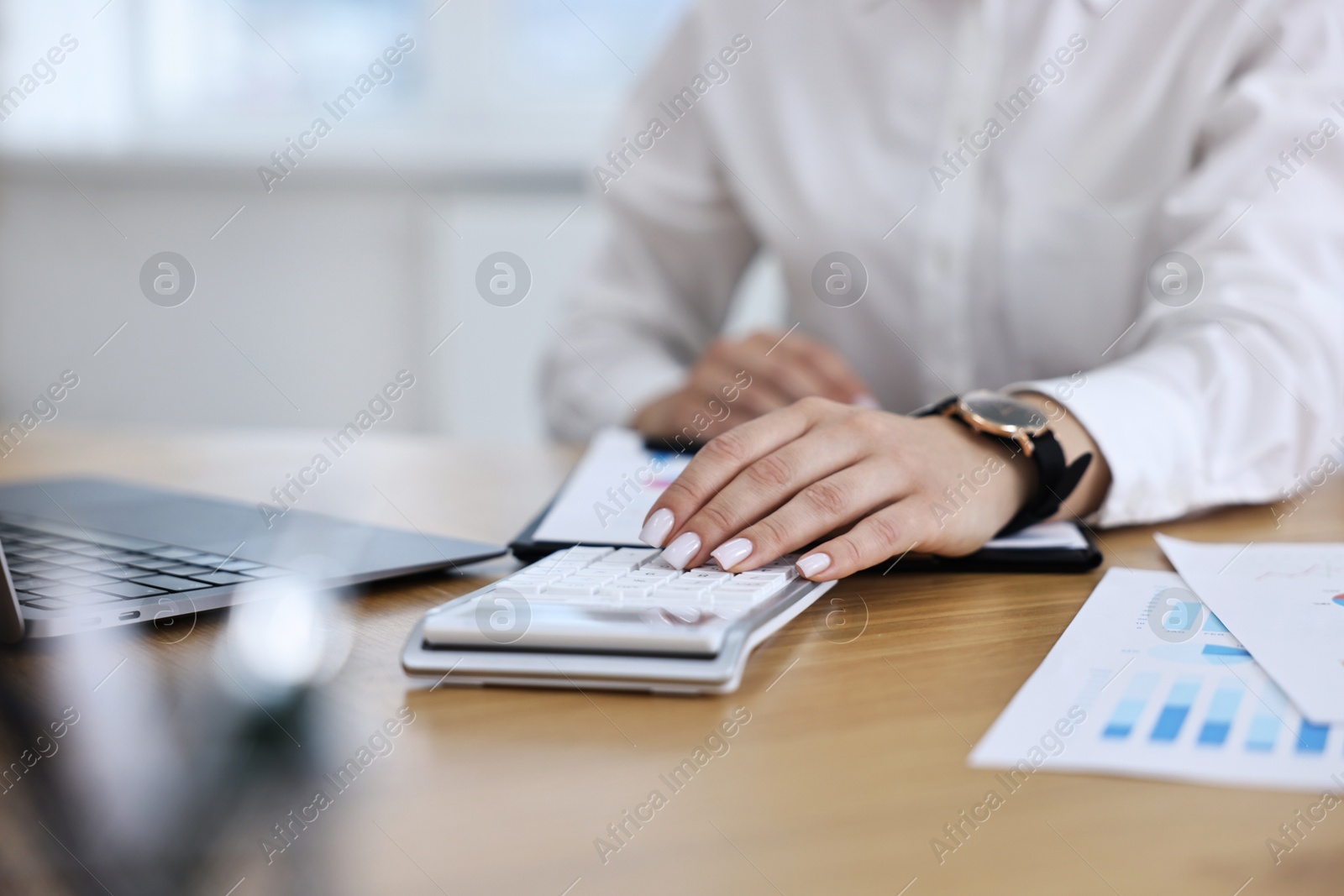 Photo of Banker using calculator at wooden table in office, closeup