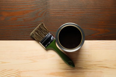 Photo of Applying walnut wood stain. Brush and can on wooden surface, flat lay