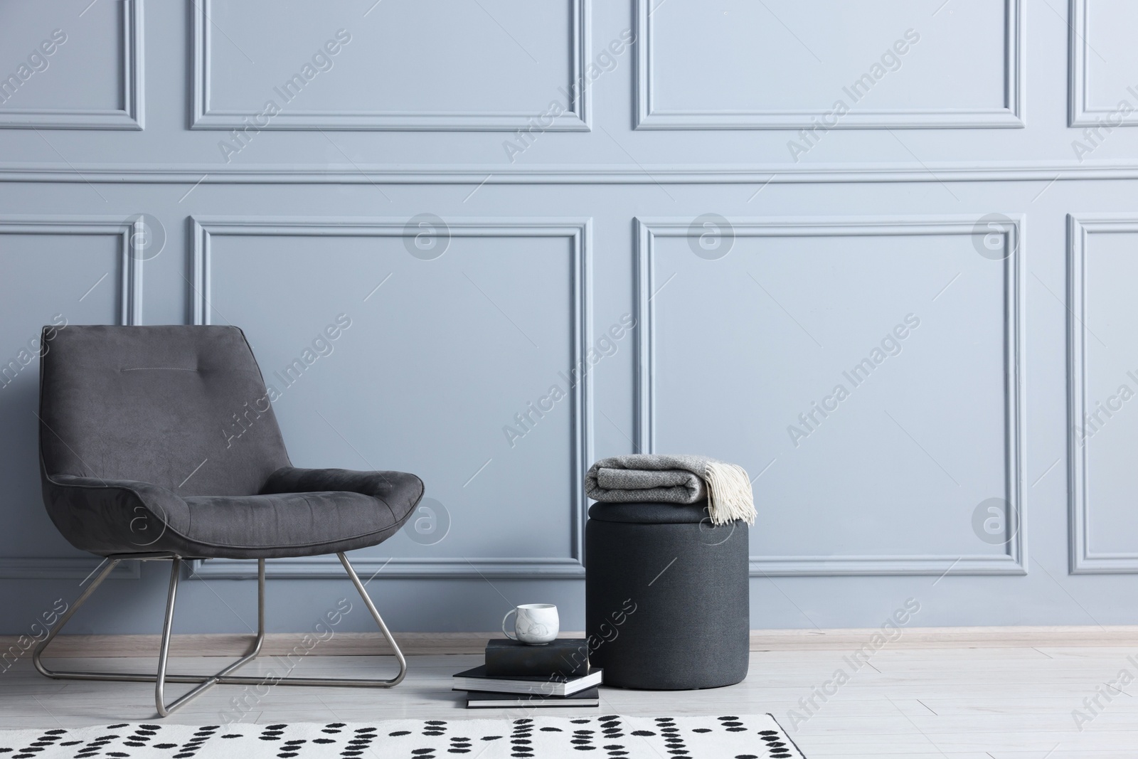 Photo of Stylish stool, chair and books near light grey wall indoors, space for text