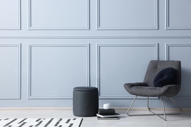 Photo of Stylish stool, chair and books near light grey wall indoors, space for text