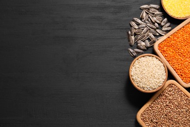 Photo of Different types of seeds, legumes and cereals on black wooden table, flat lay. Space for text