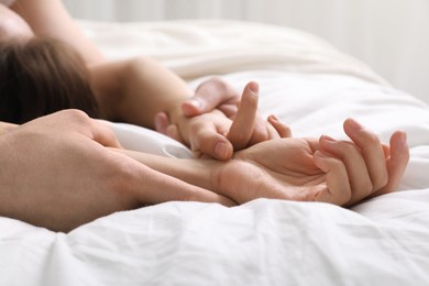 Lovely couple holding hands in bed, closeup