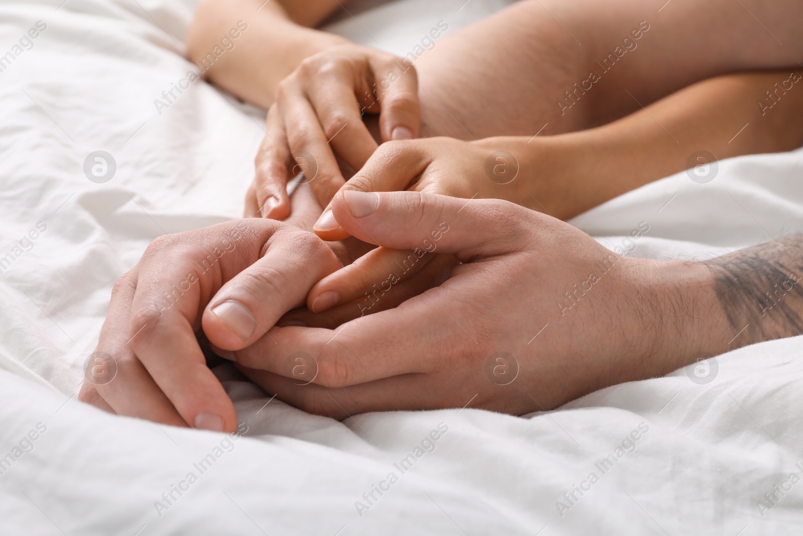 Photo of Lovely couple holding hands in bed, closeup