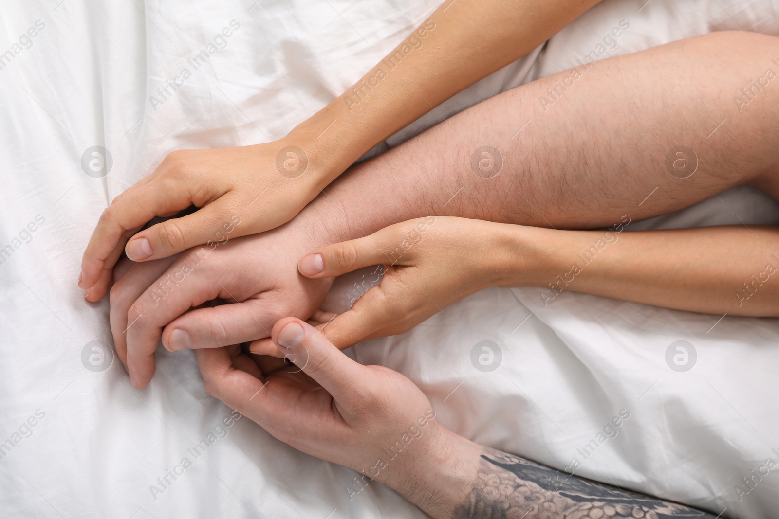 Photo of Lovely couple holding hands in bed, top view.