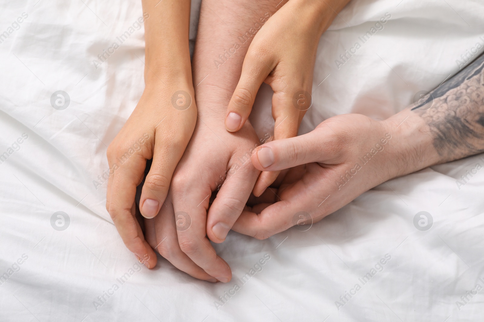 Photo of Lovely couple holding hands in bed, top view.