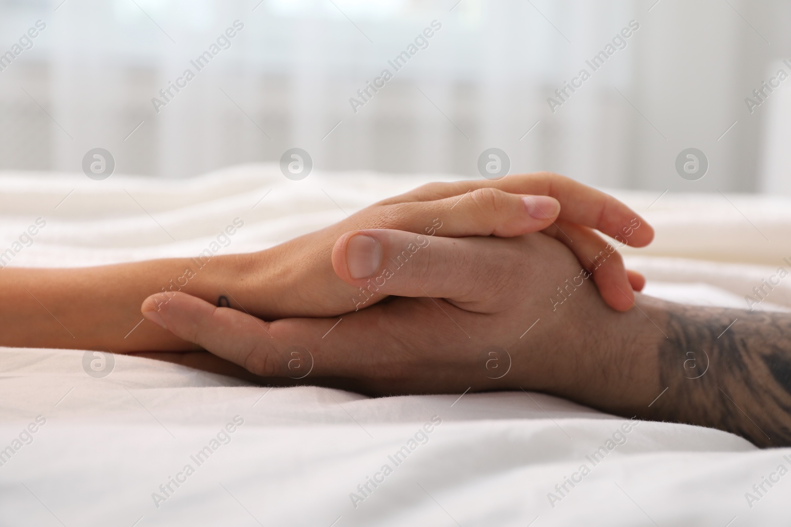 Photo of Lovely couple holding hands in bed, closeup