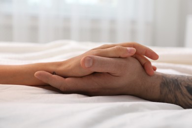 Lovely couple holding hands in bed, closeup