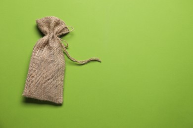 Photo of One burlap sack on light green background, top view. Space for text