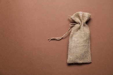 Photo of One burlap sack on brown background, top view. Space for text