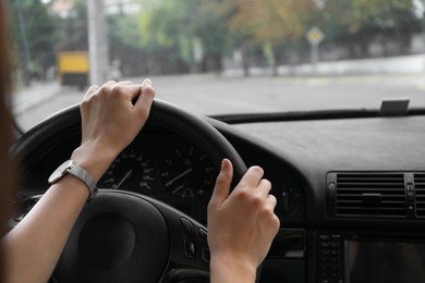 Woman holding steering wheel while driving car, closeup