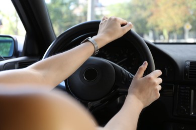 Woman holding steering wheel while driving car, closeup