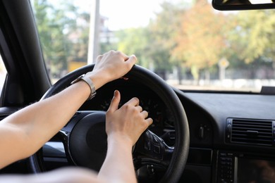 Woman holding steering wheel while driving car, closeup