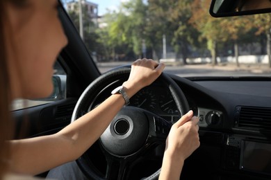 Woman holding steering wheel while driving car, closeup