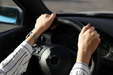 Woman holding steering wheel while driving car, closeup