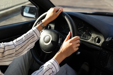 Woman holding steering wheel while driving car, closeup