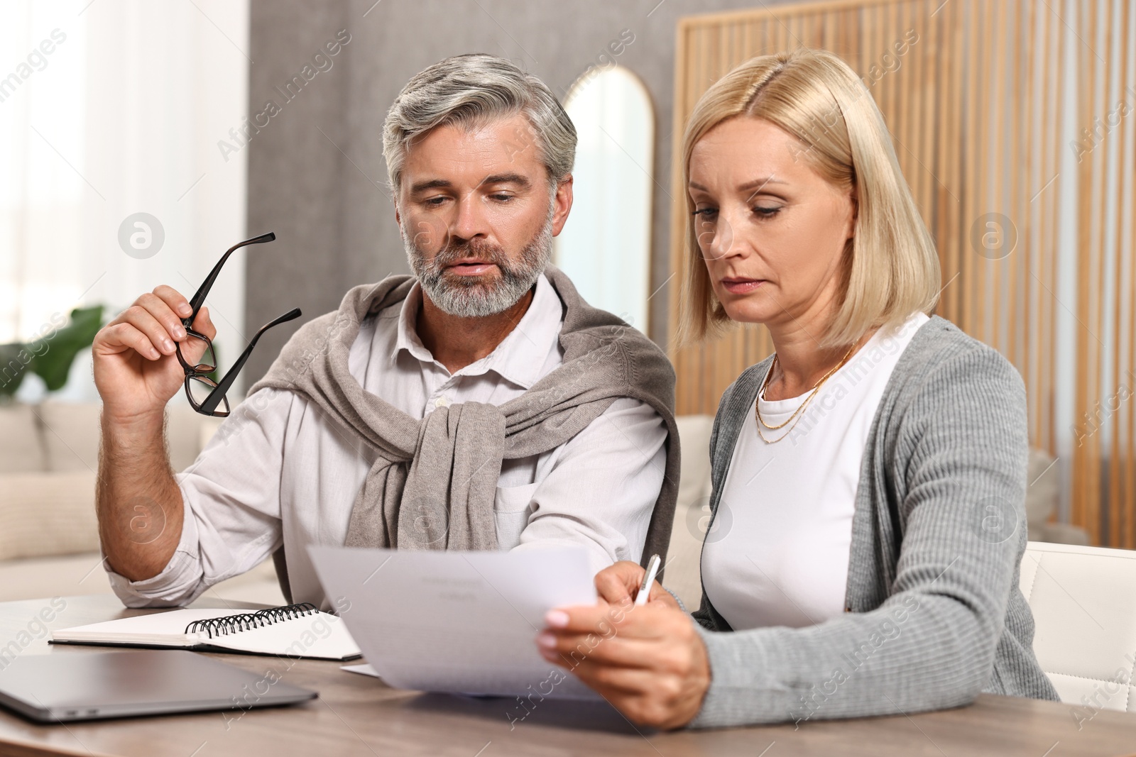 Photo of Couple planning pension budget at table indoors