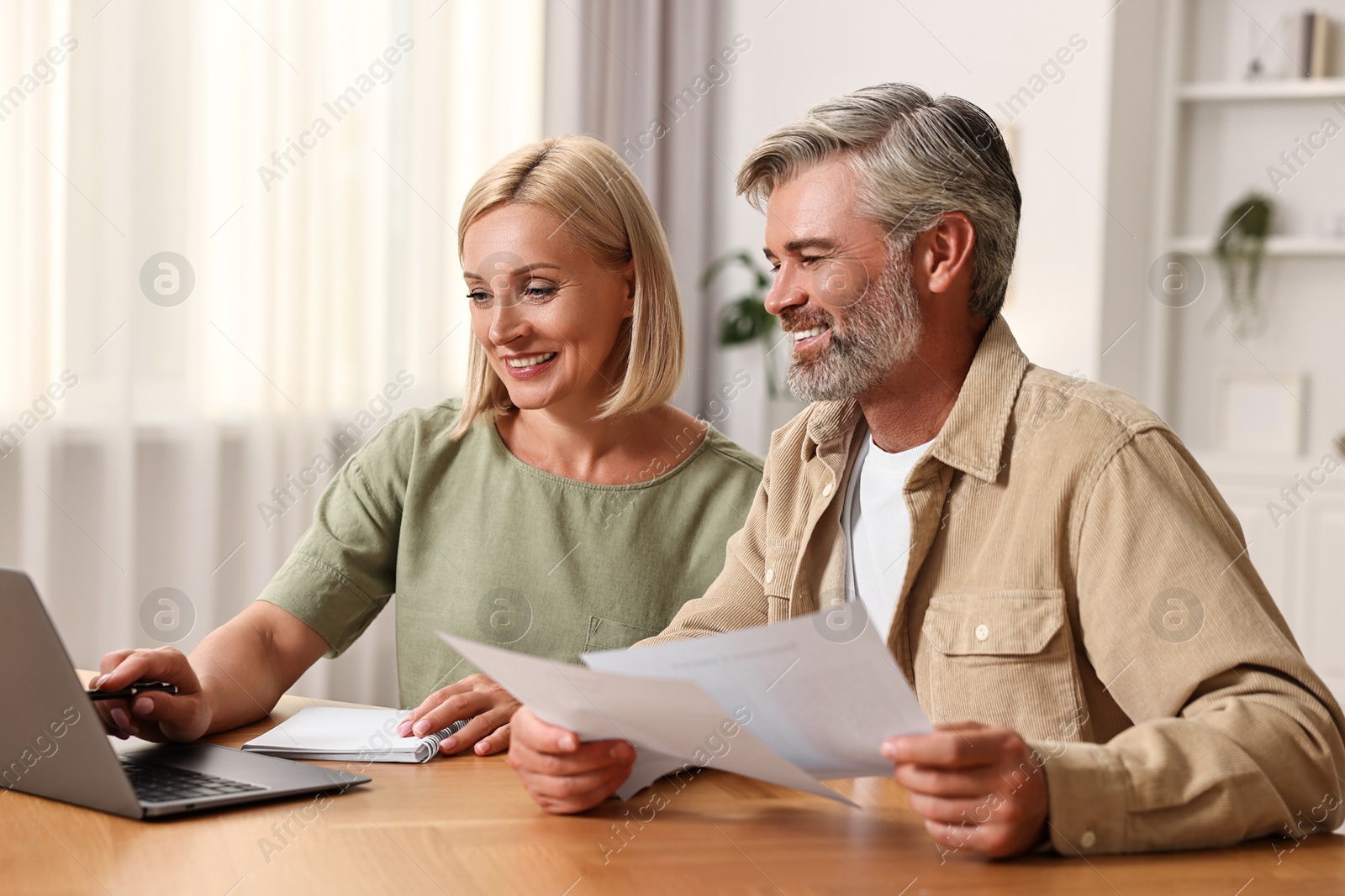 Photo of Couple planning pension budget at table indoors