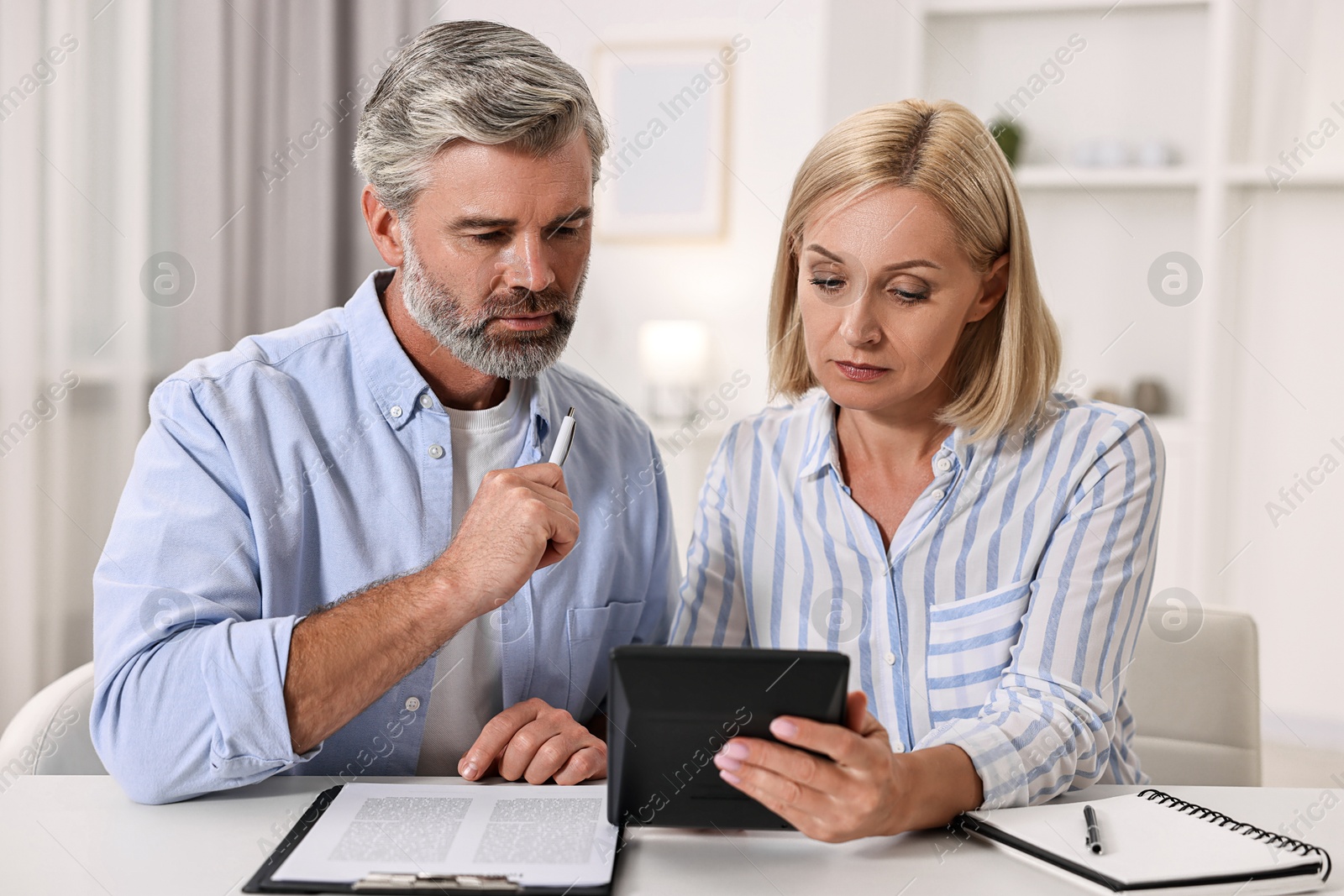 Photo of Pension savings. Couple planning budget at table indoors