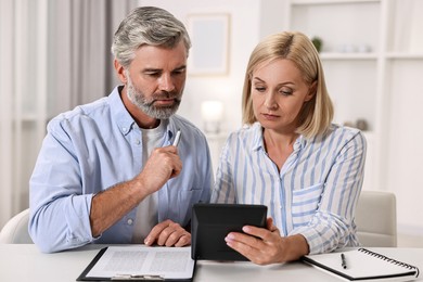 Photo of Pension savings. Couple planning budget at table indoors