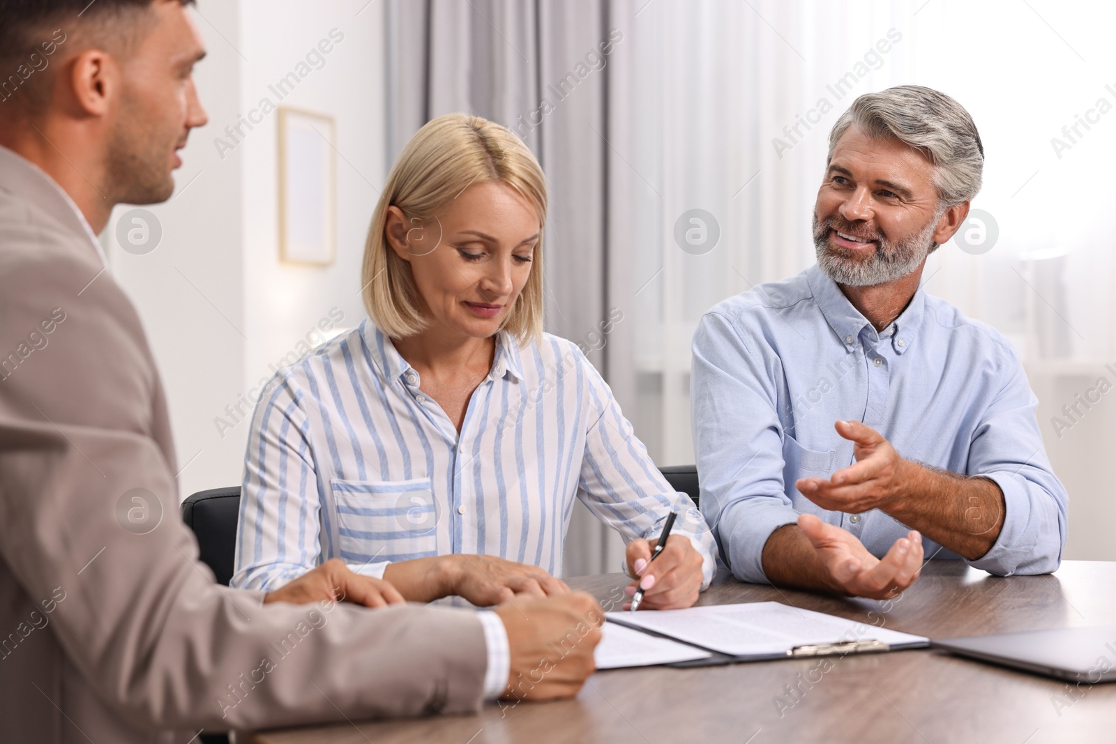 Photo of Pension plan. Couple consulting with insurance agent at table indoors