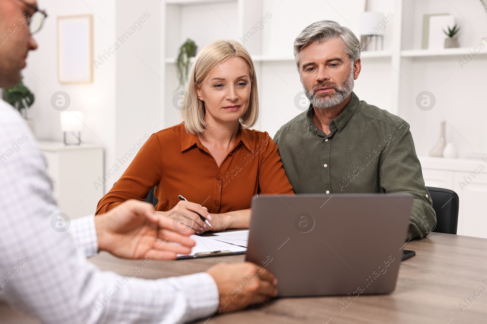 Photo of Pension plan. Couple consulting with insurance agent at table indoors