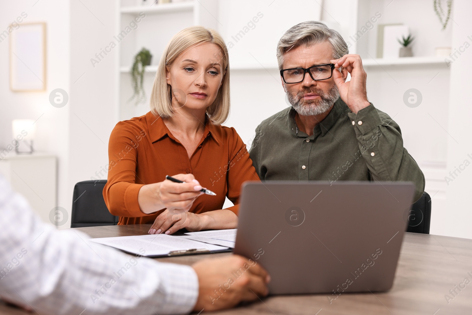 Photo of Pension plan. Couple consulting with insurance agent at table indoors