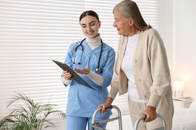 Photo of Nurse helping senior woman with walking frame in clinic