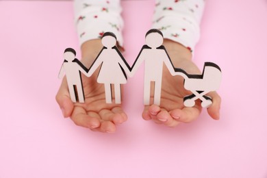 Photo of Adoption. Little girl with figures of family on pink background, closeup