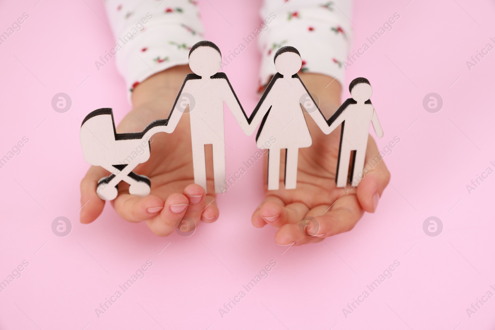 Photo of Adoption. Little girl with figures of family on pink background, closeup