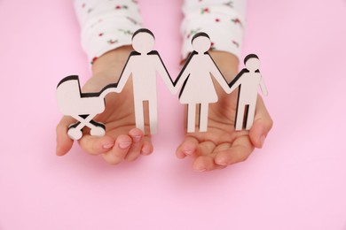 Photo of Adoption. Little girl with figures of family on pink background, closeup