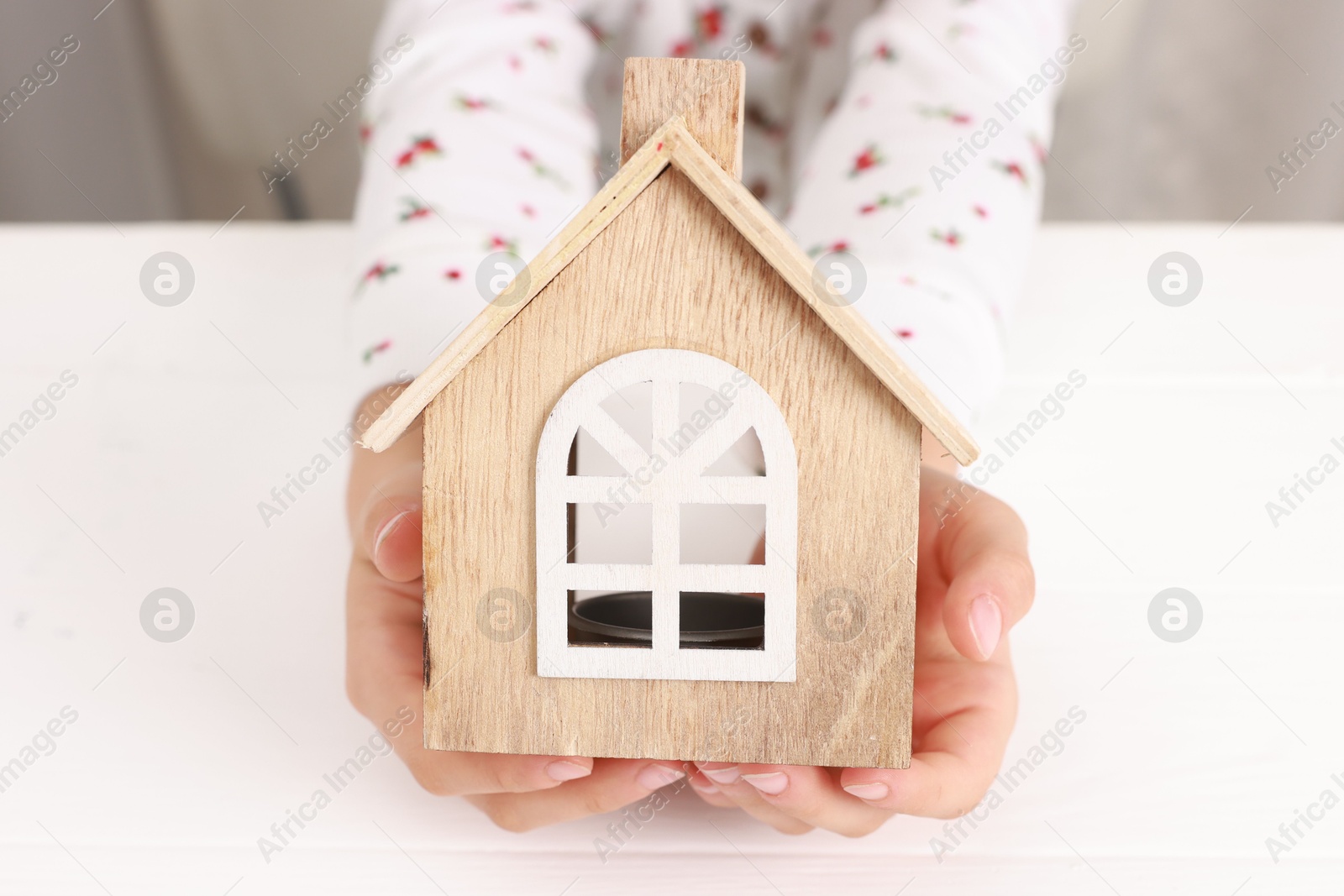 Photo of Adoption. Little girl with house figure at white table, closeup