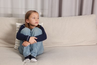 Autism concept. Lonely little girl on sofa at home